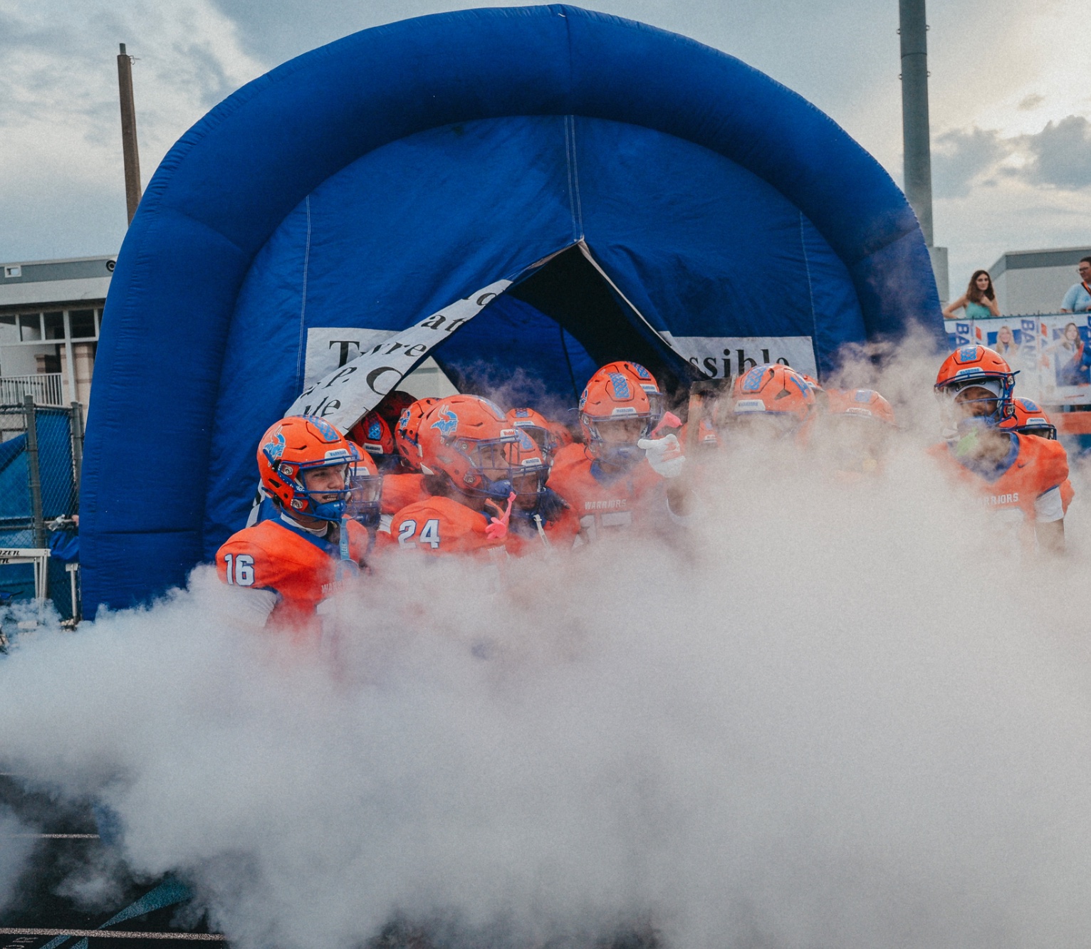 West Orange Warriors football players entering the field through smoke.